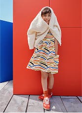 A child in a striped dress against a red background