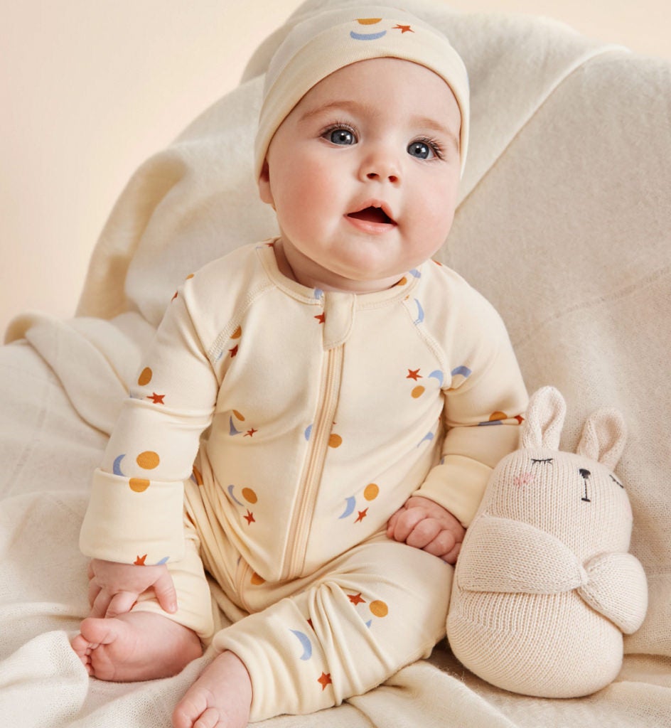 baby wearing a yellow baby sleeper and matching hat
